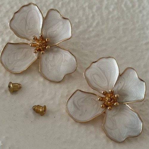 نمای نزدیک گوشواره میخی طرح گل چهارپر با لعاب سفید صدفی و لبهها و پرچمهای طلایی