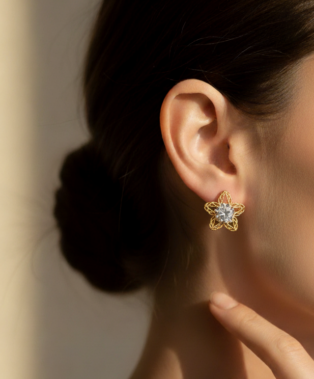 گوشواره میخی استیل طلایی طرح ستاره مشبک با نگین درشت مرکزی روی گوش